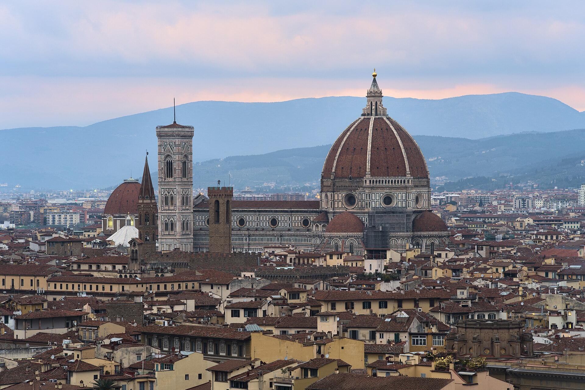 Florence Cathedral with Brunelleschi’s dome and Giotto’s bell tower rising above the rooftops of the old town at dusk, seen from Piazzale Michelangelo with hills behind