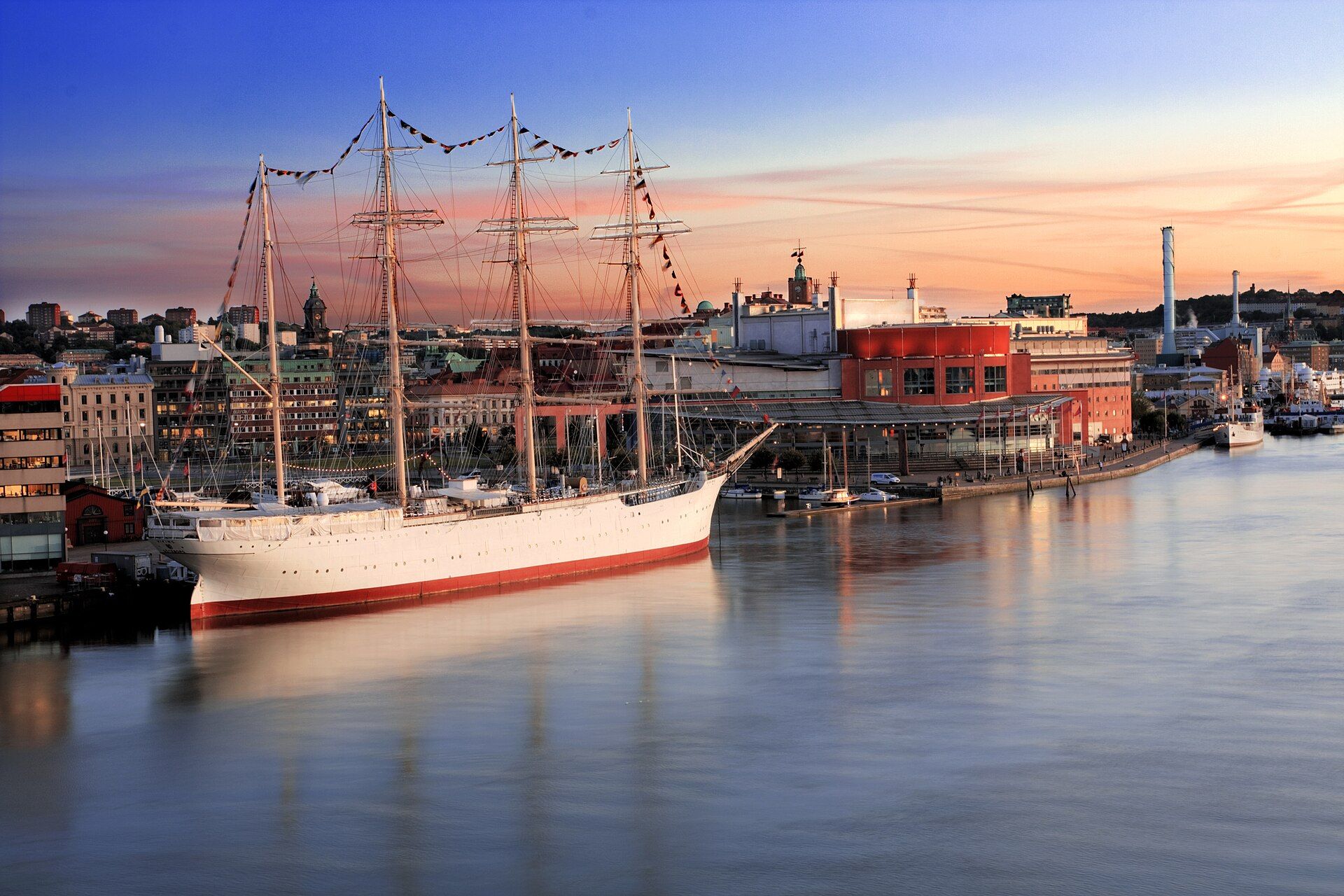 The four-masted barque Viking moored at Lilla Bommen in Gothenburg at sunset, with the opera house and the city skyline behind
